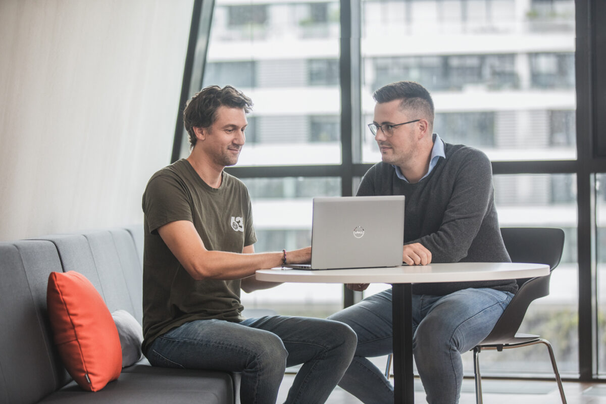 Zwei Kollegen in einer IT-Firma , schauen in einen Laptop und besprechen sich. Unternehmensfotogafie vom Fotograf in Köln.