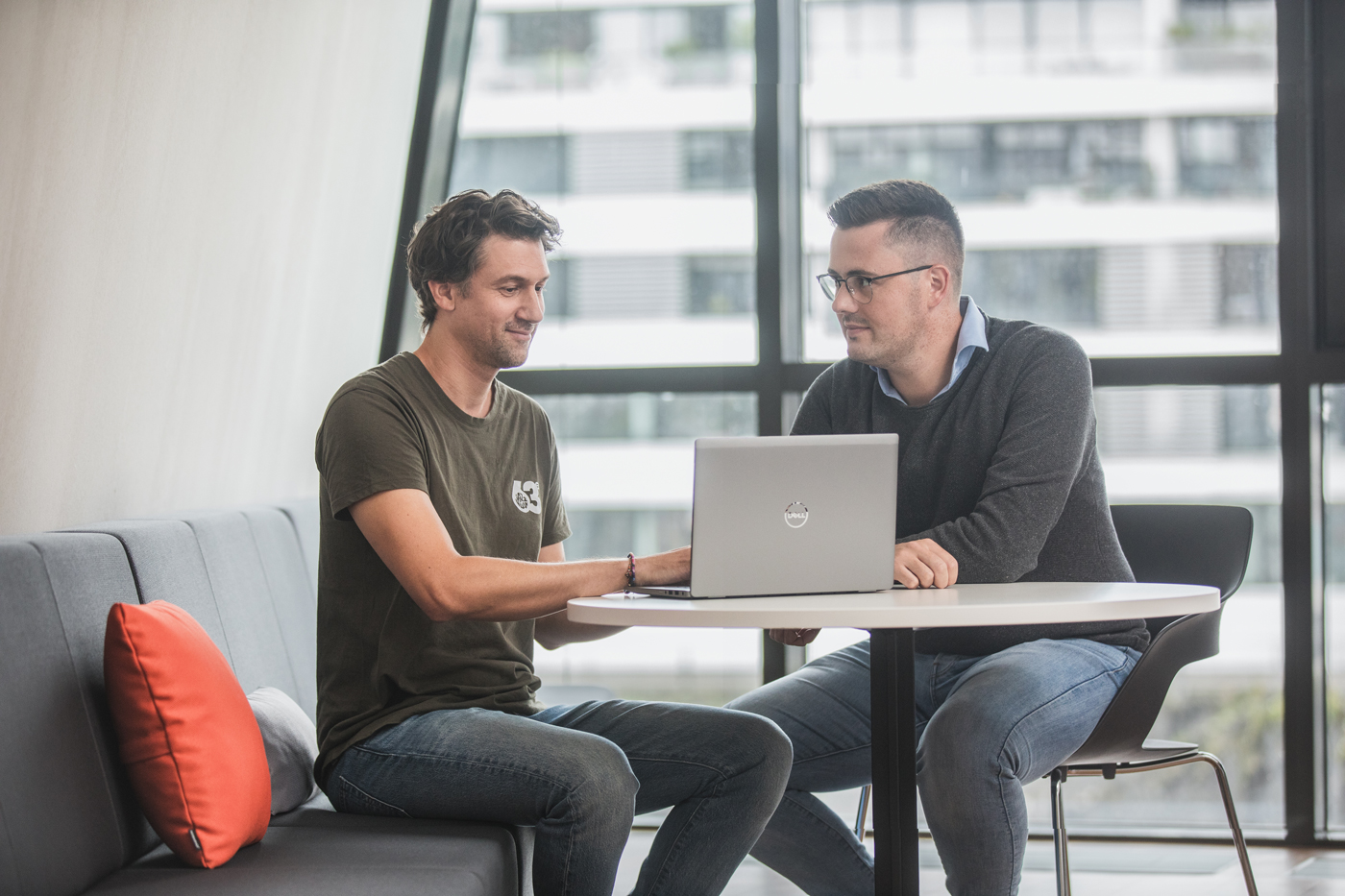Zwei Kollegen in einer IT-Firma , schauen in einen Laptop und besprechen sich. Unternehmensfotogafie vom Fotograf in Köln.